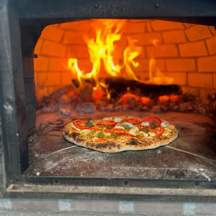 Neapolitan-style pizza cooking with visible flame inside the Lisboa Azul oven’s fire brick interior