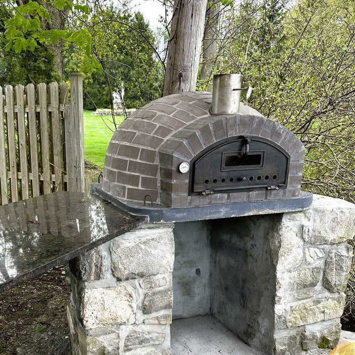 Lume Largo Tudo Pizza Oven installed outdoors on rustic stone base, chimney visible