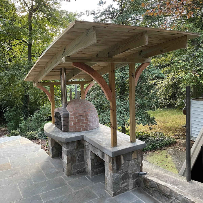 Rustic Lisboa pizza oven installed under pergola in outdoor kitchen