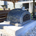 Rustic Pizzaioli Premium Pizza Oven by Authentic Pizza Ovens in stacked stone finish, shown from side angle on outdoor countertop