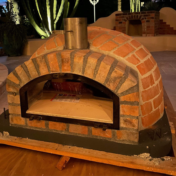 Rustic Pizzaioli Premium Pizza Oven at night with dome and chimney visible